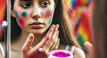 Young woman with Holi colors on her face applying ointment to soothe skin irritation while looking in a mirror.